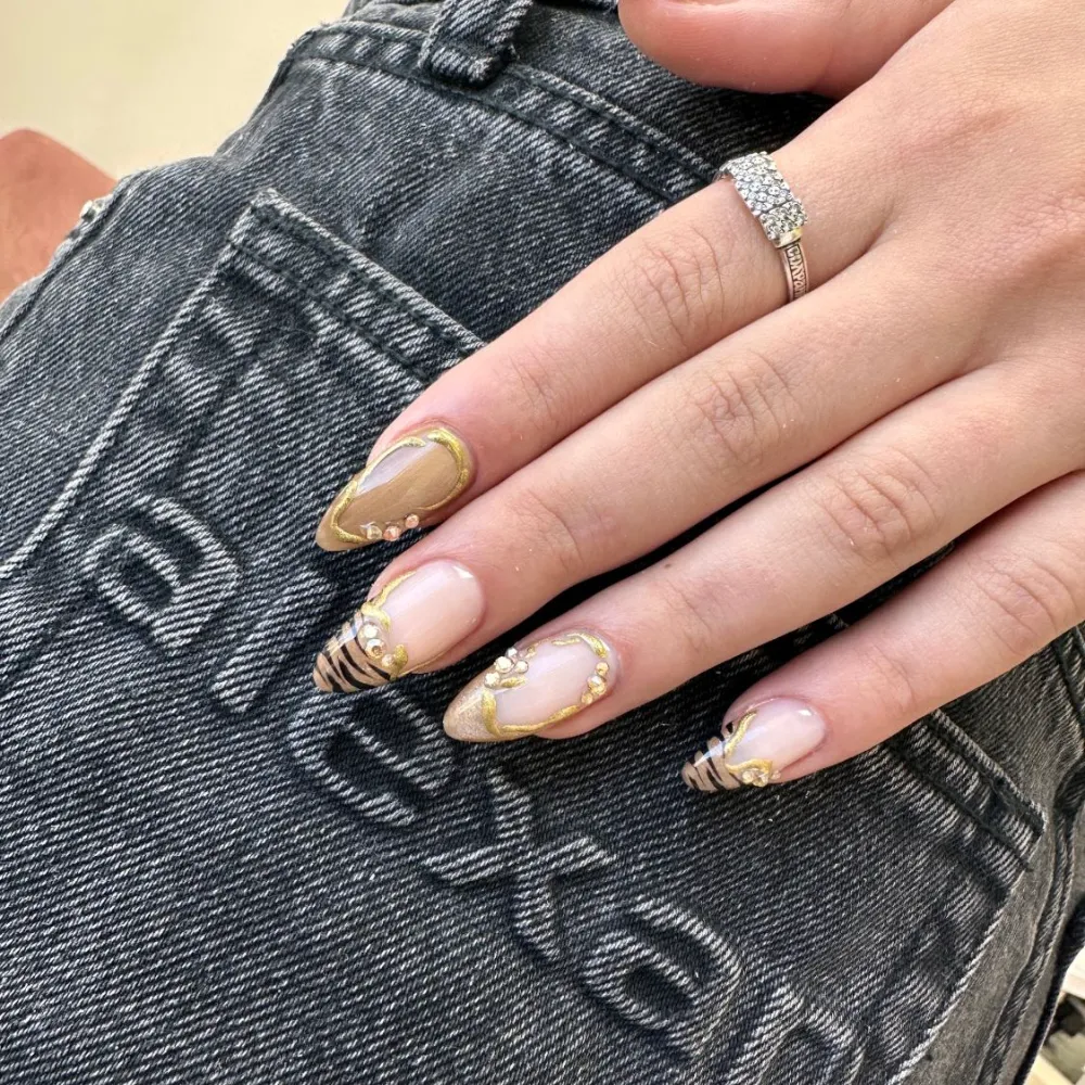 Uñas almendradas con líneas doradas, cristales y puntas con rayas de tigre