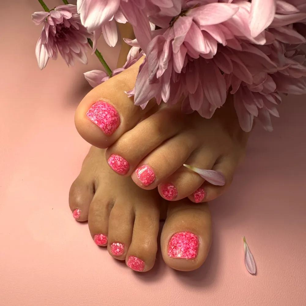 Pedicura en gel rosa con glitter y crisantemos lila