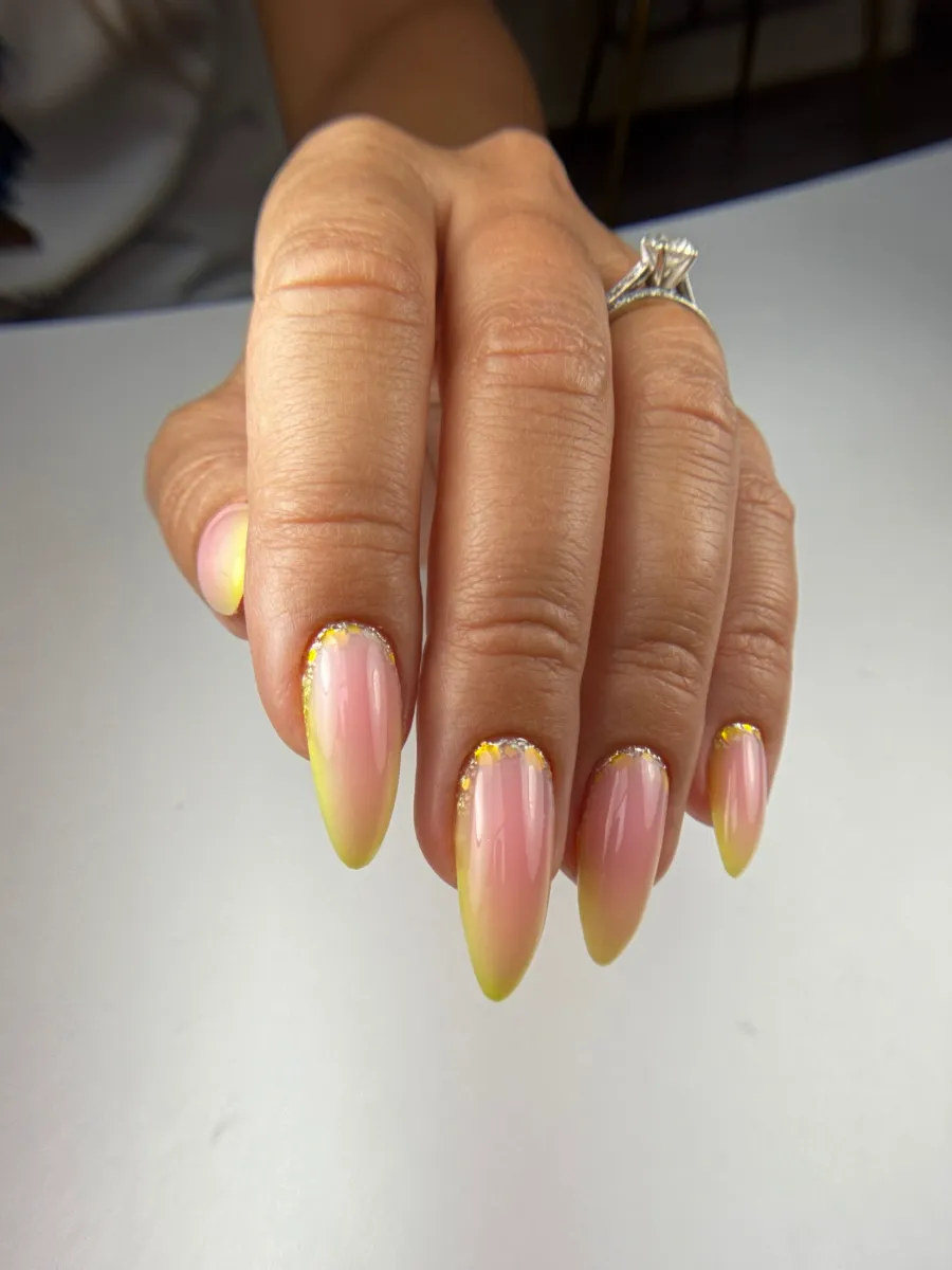 Uñas almendradas largas con ombré de rosa a amarillo y foil dorado junto a la cutícula