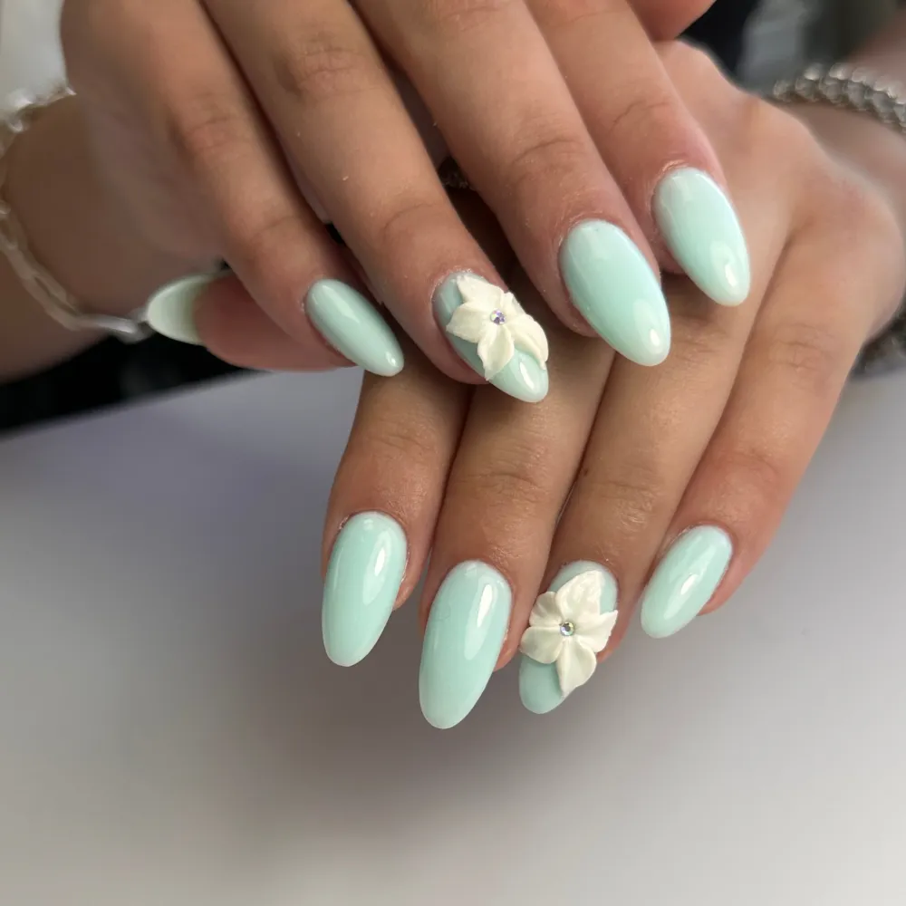 Glossy mint almond manicure with sculpted white 3D flowers
